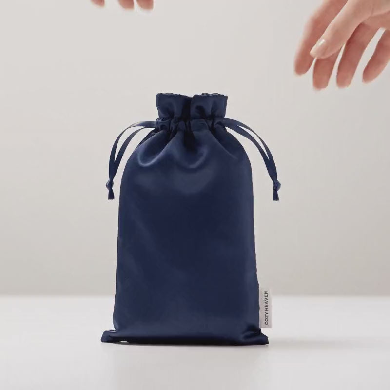 Die Luxus Lyocell Schlafmaske in Deep Blue wird aus der passenden Reisetasche genommen, aufgefaltet und aufgelegt.