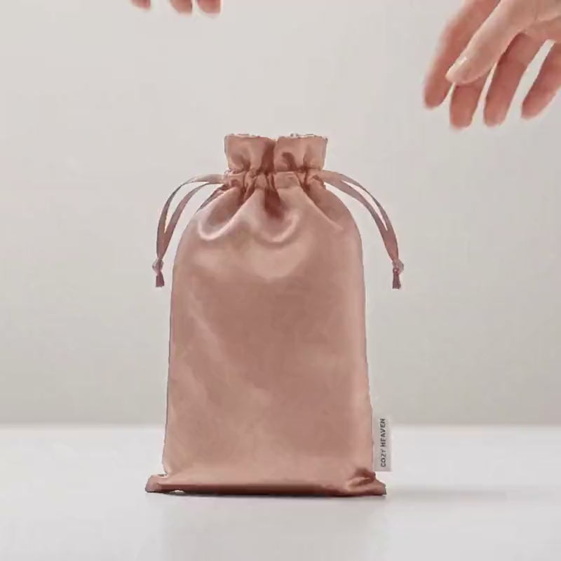 Die Luxus Lyocell Schlafmaske in Light Rose wird aus der Reisetasche genommen, aufgefaltet und aufgelegt.