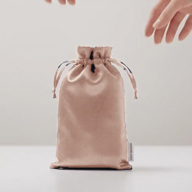 Die Luxus Lyocell Schlafmaske in Light Rose wird aus der Reisetasche genommen, aufgefaltet und aufgelegt.